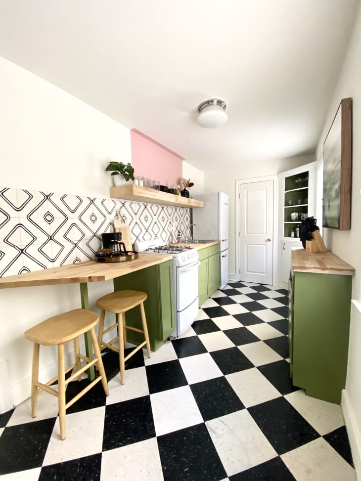 厨房与黑色和白色棋盘地板，绿色低柜，和钻石图案的后挡板