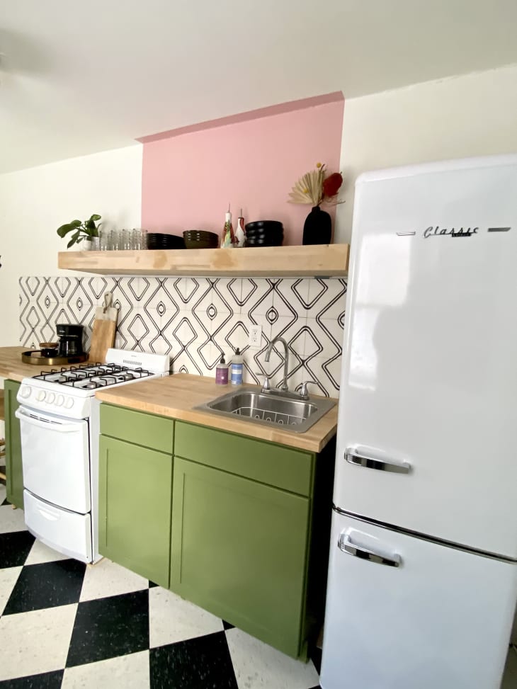 厨房有绿色橱柜，钻石图案的后挡板和老式冰箱