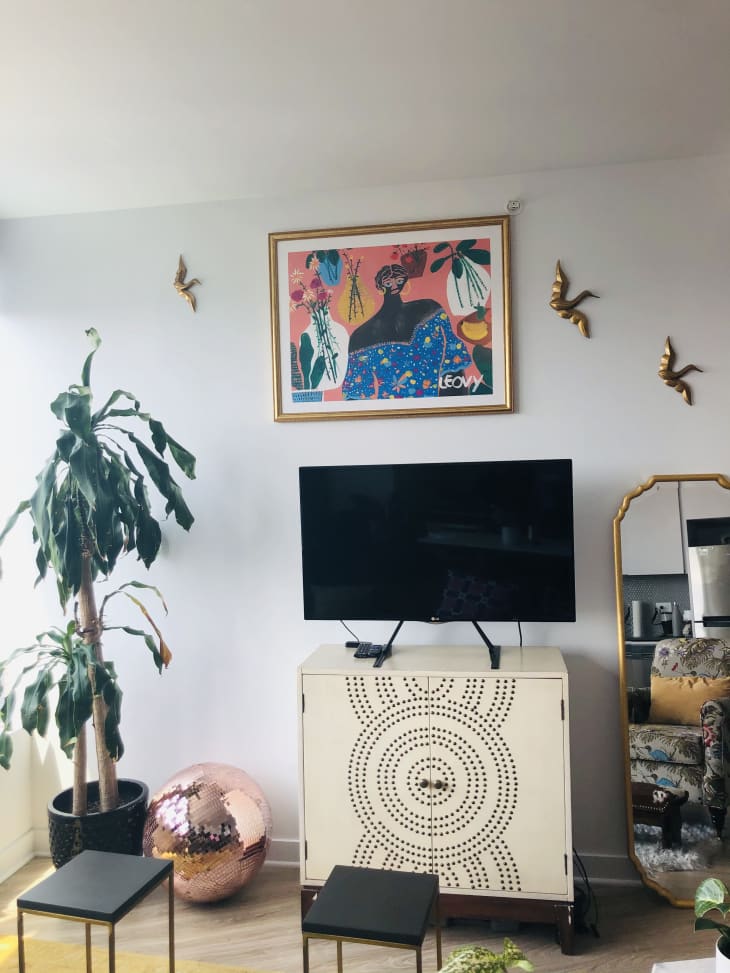 TV on top of cabinet and colorful artwork on wall above