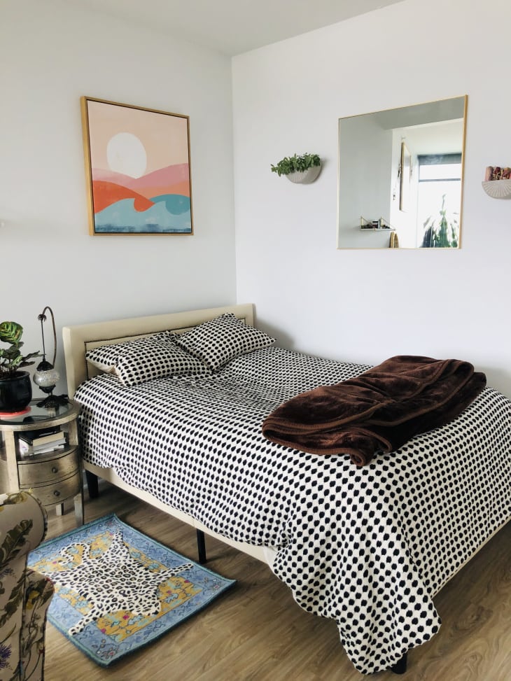 Bed with dotted bedspread in corner of apartment