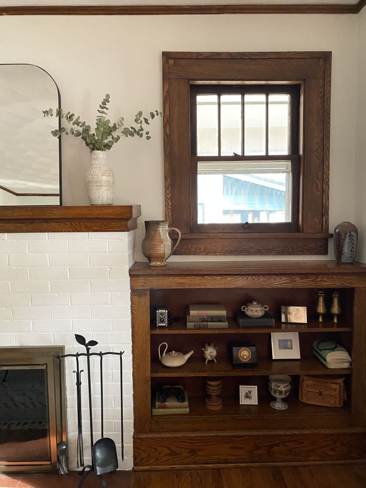 Shelf with knick knacks beneath window to the right of fireplace