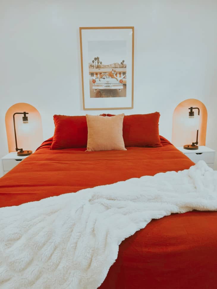 Bedroom with red bedding and painted arches behind side tables