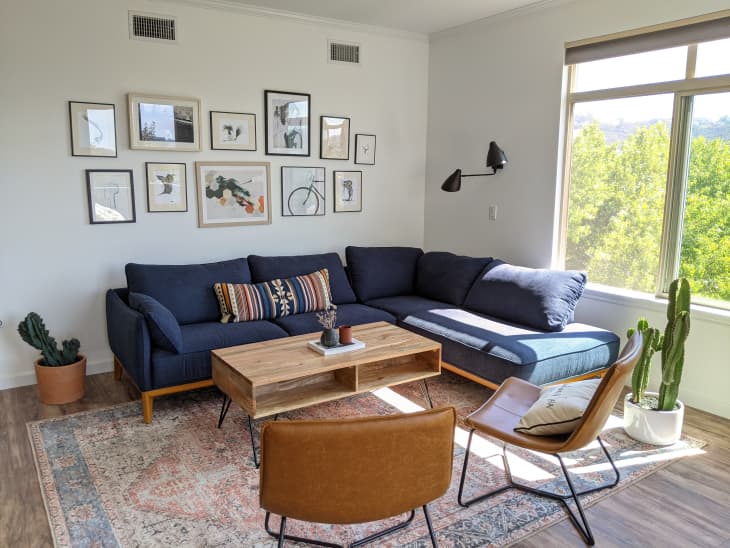 Sunny living room with blue sectional, leather accent chairs, and vintage rug