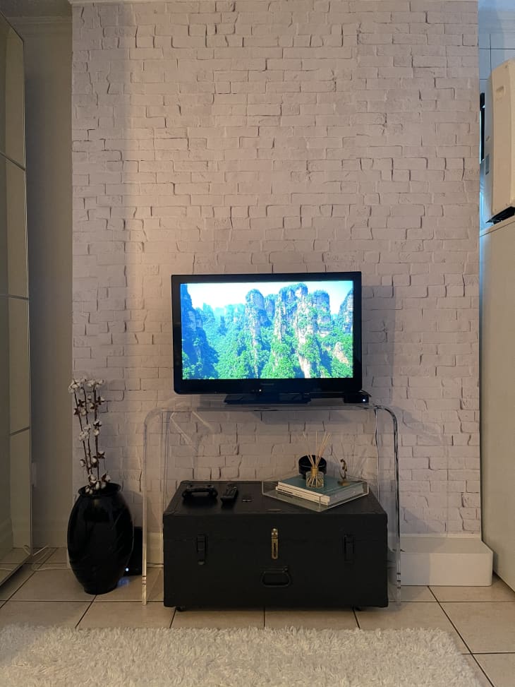 TV on acrylic console table with old trunk underneath it