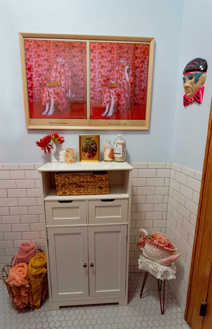 Framed red artwork above cabinet in bathroom