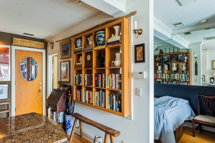 A wooden bookcase built into the wall of a studio apartment