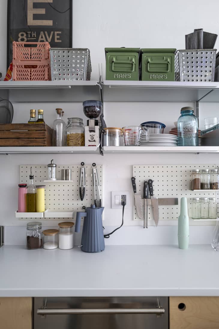 Extremely organized modern kitchen with peg board storage and baskets on shelves.