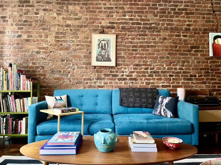 blue couch in front of brick wall