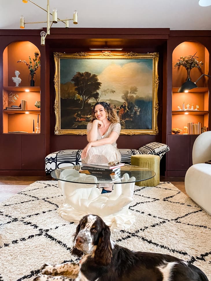woman and dog sit in living room in front of large painting