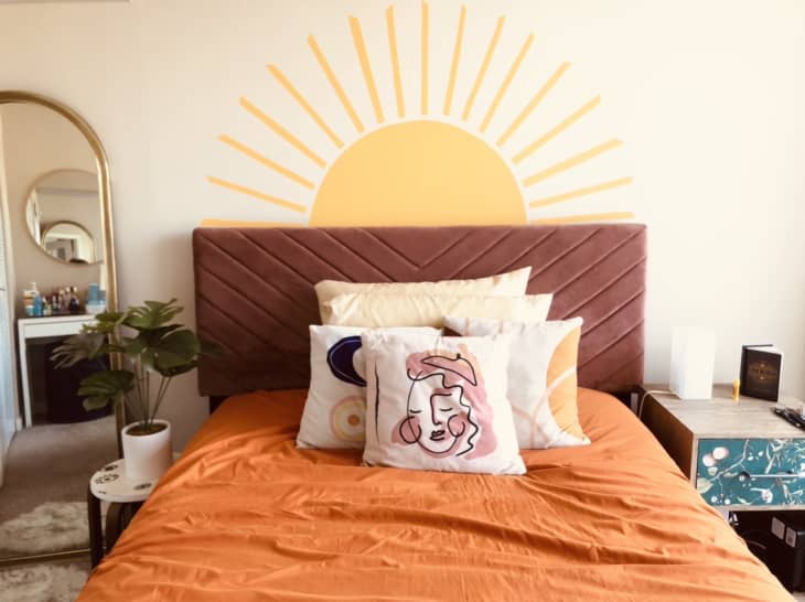 Orange bed with sun painted on wall behind