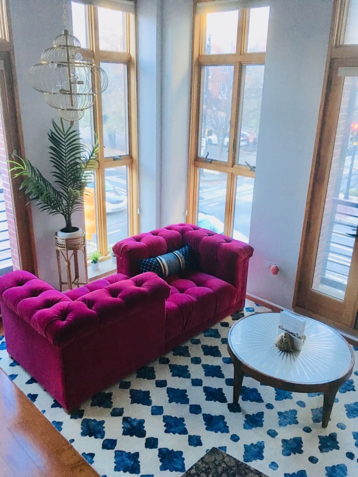 Pink velvet corner sofa next to floor to ceiling windows