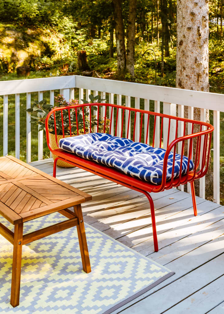 A deck with red benches and blue and white cushions next to a wooden table.