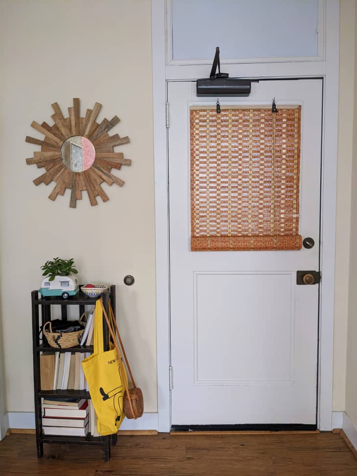 Entryway with white door and sun shaped mirror