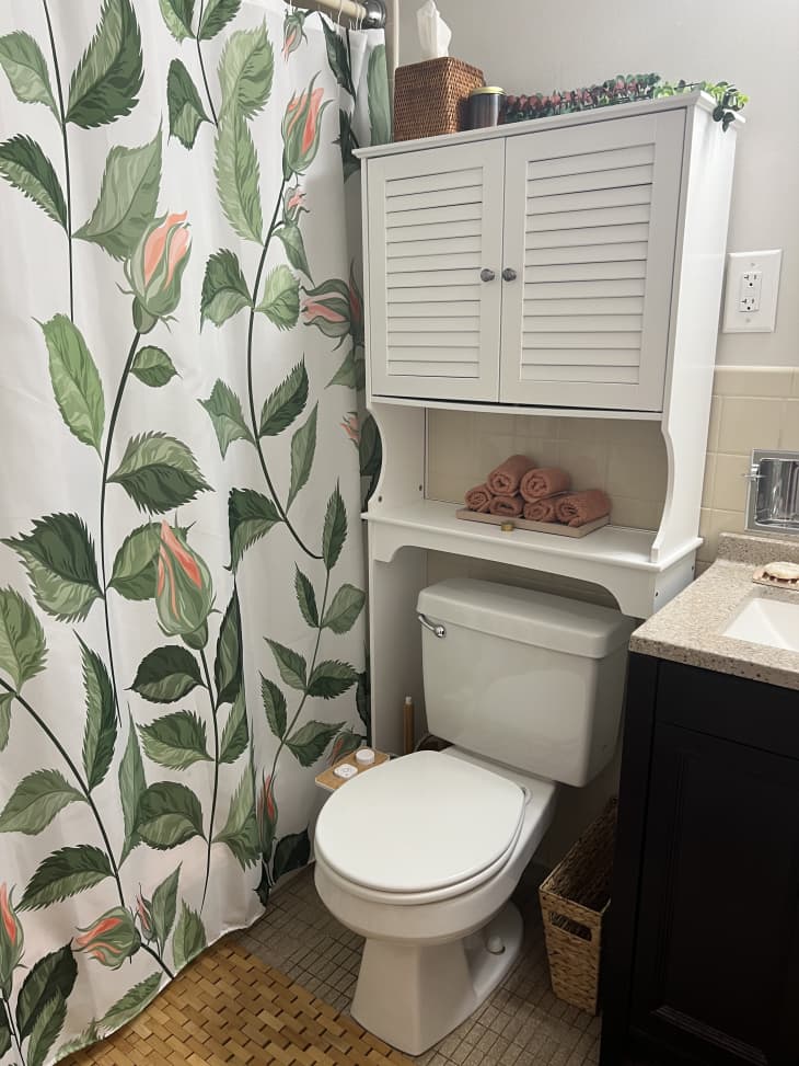 Bathroom with cabinet above toilet and floral shower curtain