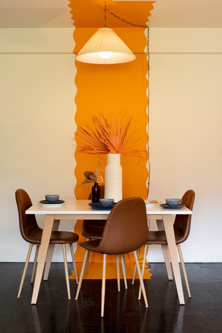 Dining table by orange stripe on wall