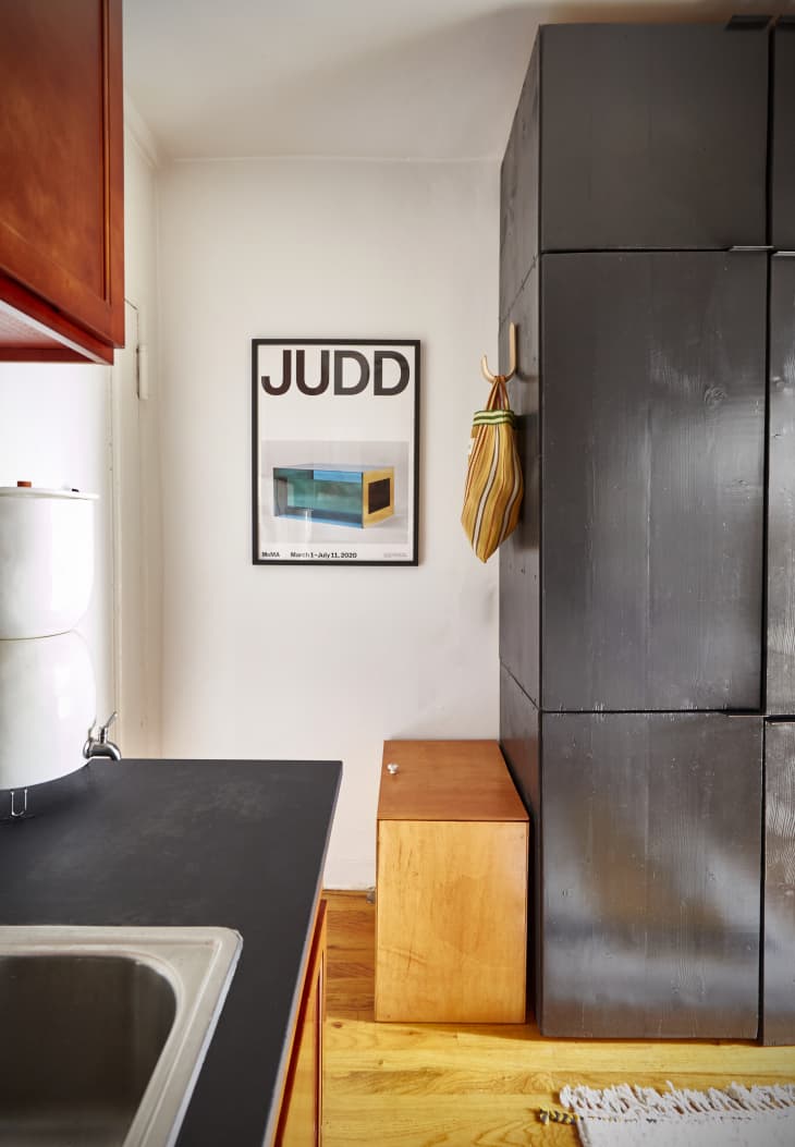 Minimal entryway with modern black DIY storage cabinets, a wood recycling box, and a Donald Judd poster