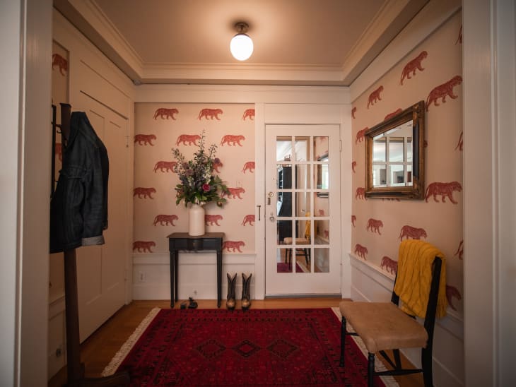 Entryway with patterned wallpaper, a reg rug, and yellow chair