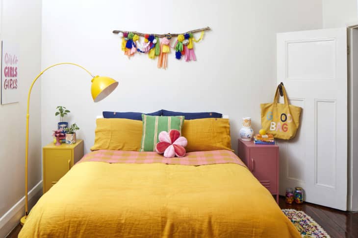 Yellow queen sized bed next to a yellow lamp