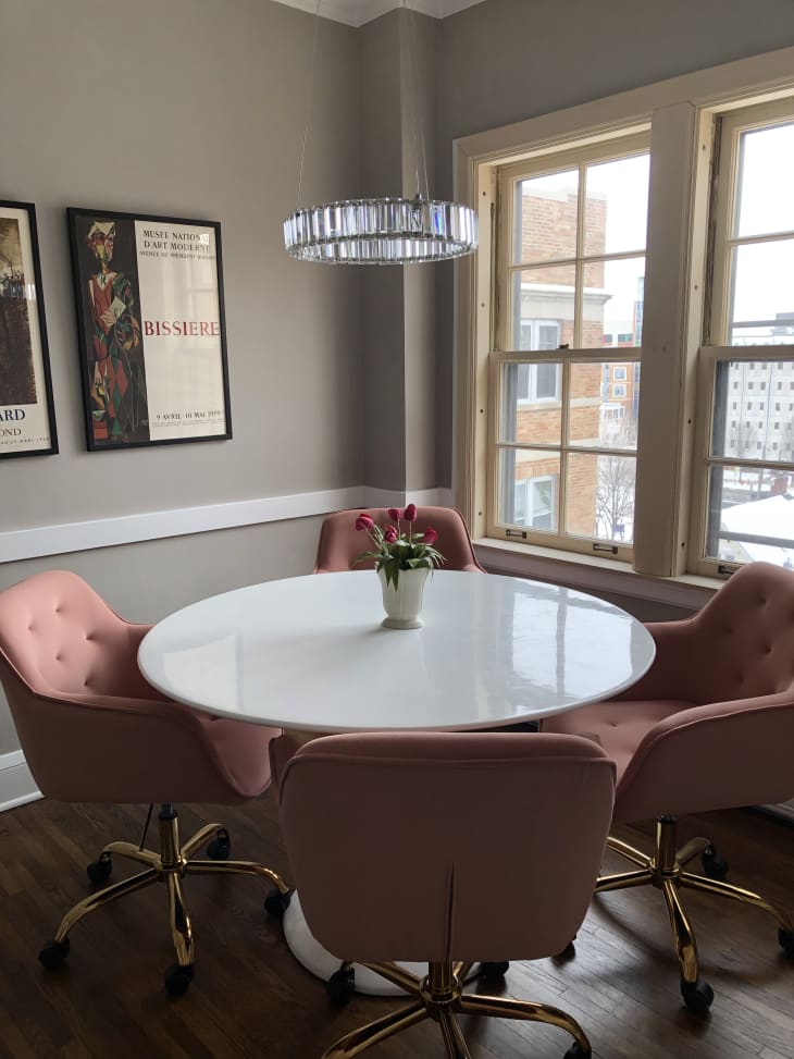 A round white dining table with four pink chairs