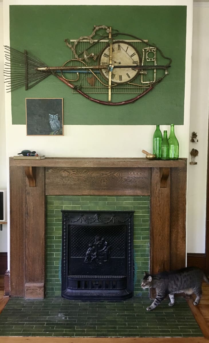 Fireplace with green fish painting hanging above it