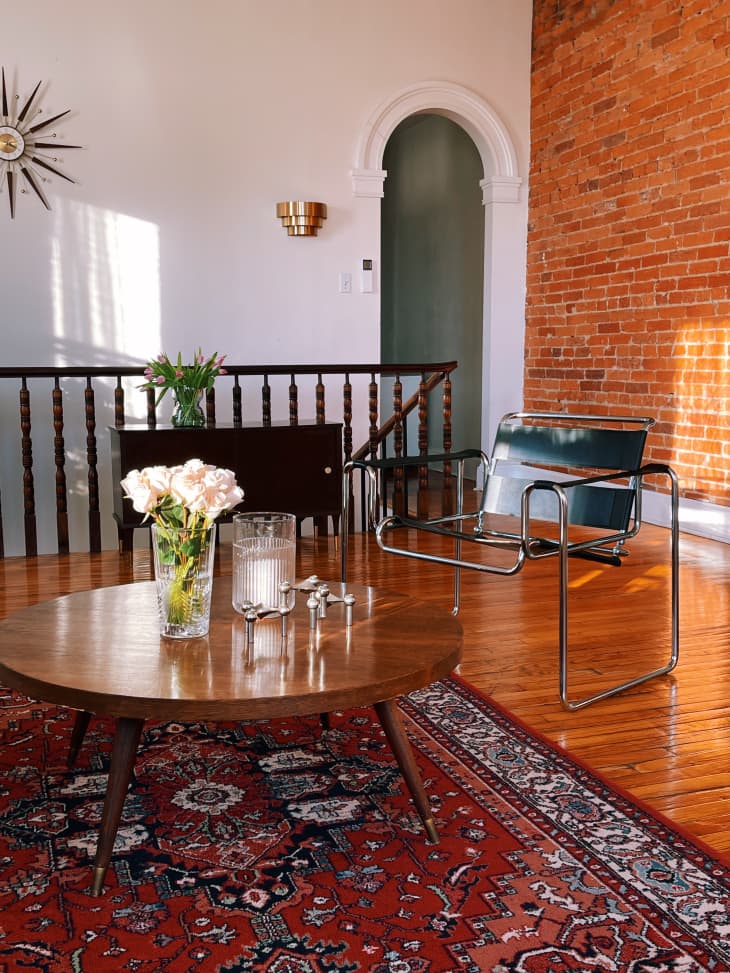 Living room with brick wall and a round coffee table on a red rug