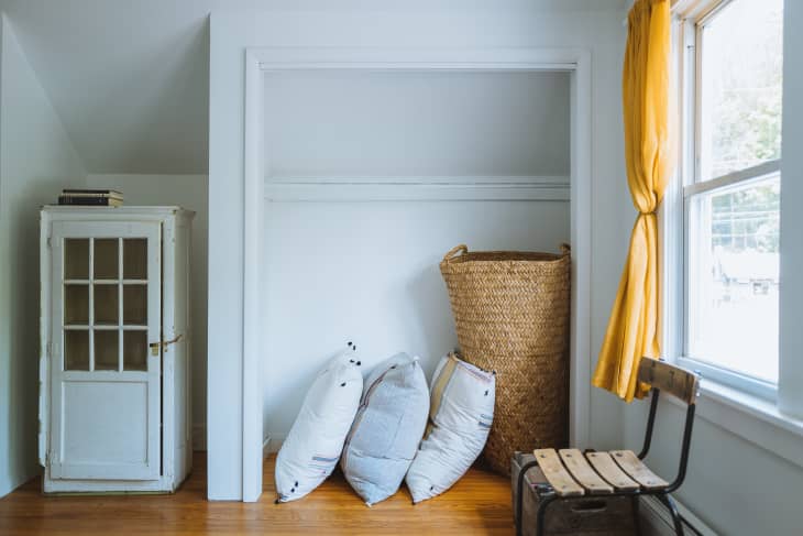 A closet with three large pillows and a wicker basket