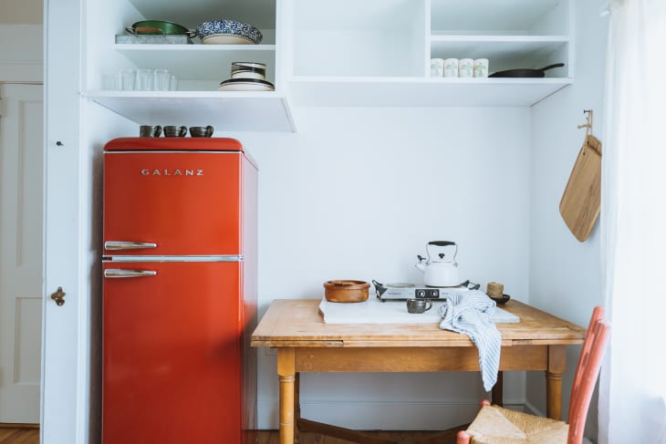 A red refrigerator next to a wooden table
