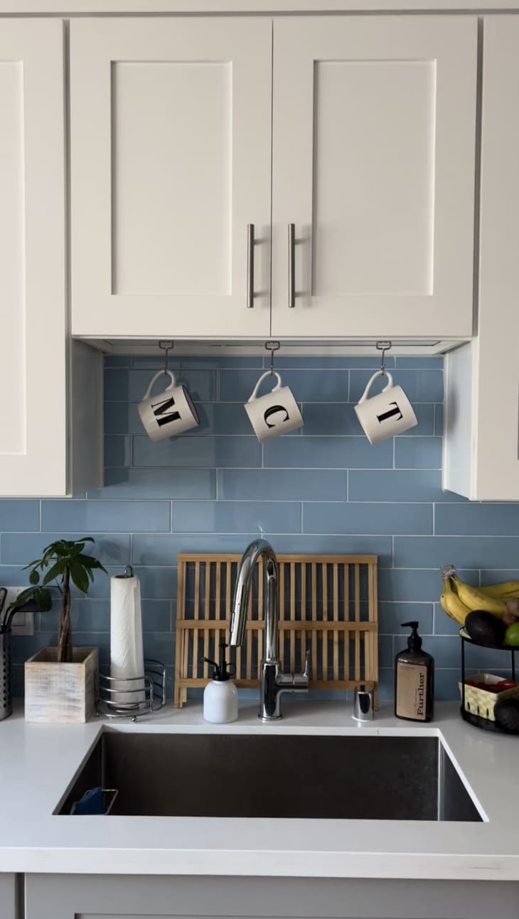 White kitchen cabinets with hanging mugs above the sink