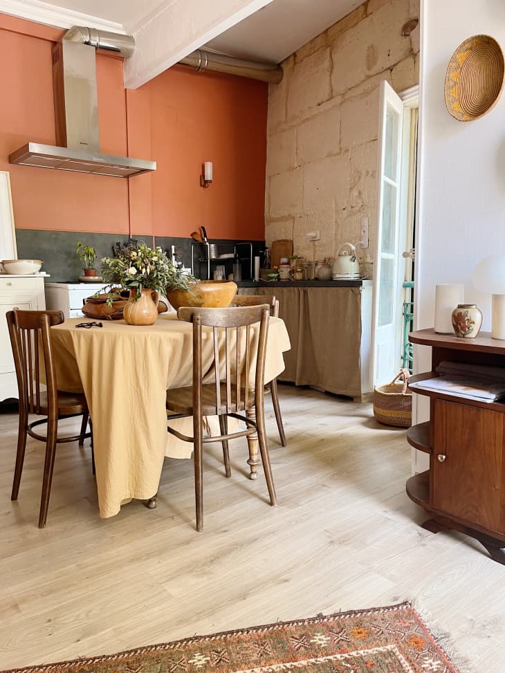 Kitchen and dining room area with wooden chairs and burnt orange cabinets