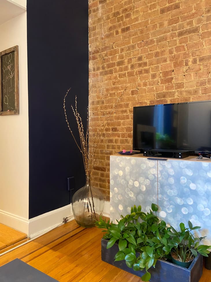A blue wall and a brick wall meet next to the tv stand