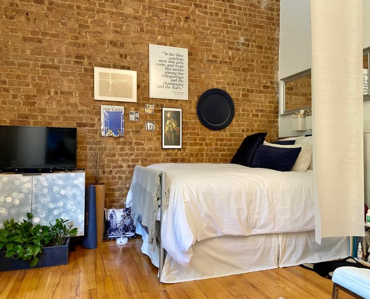 A tv stand and bed next to a brick wall