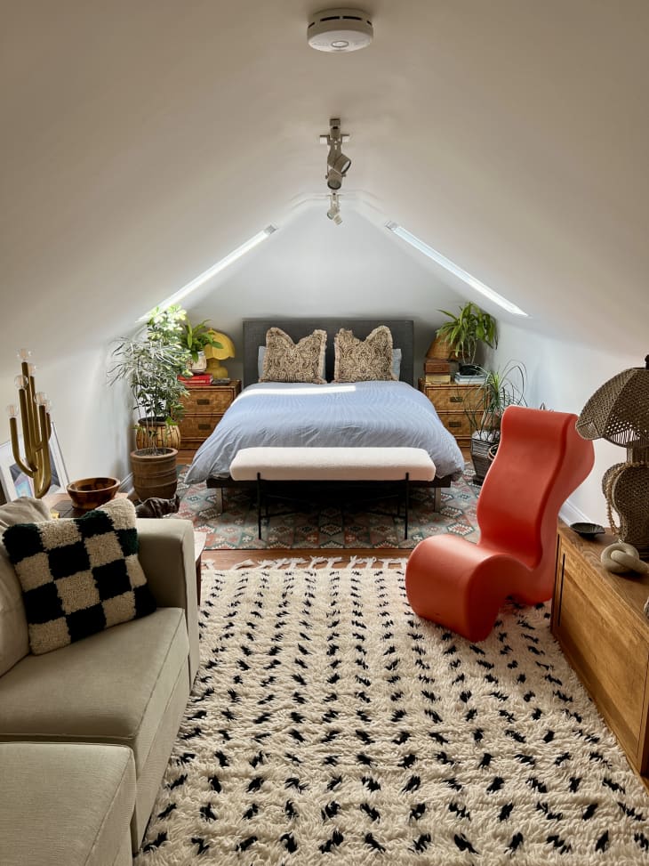 A long bedroom with a couch and triangular ceiling