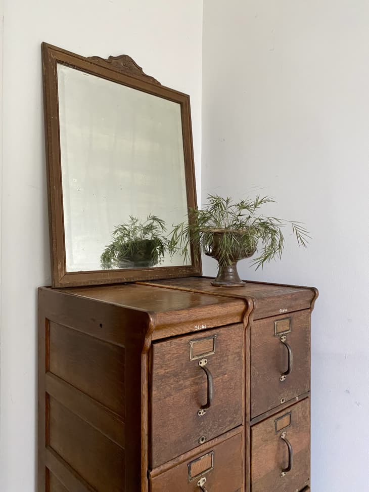 一个棕色的梳妆台，上面有一面方形镜子和植物