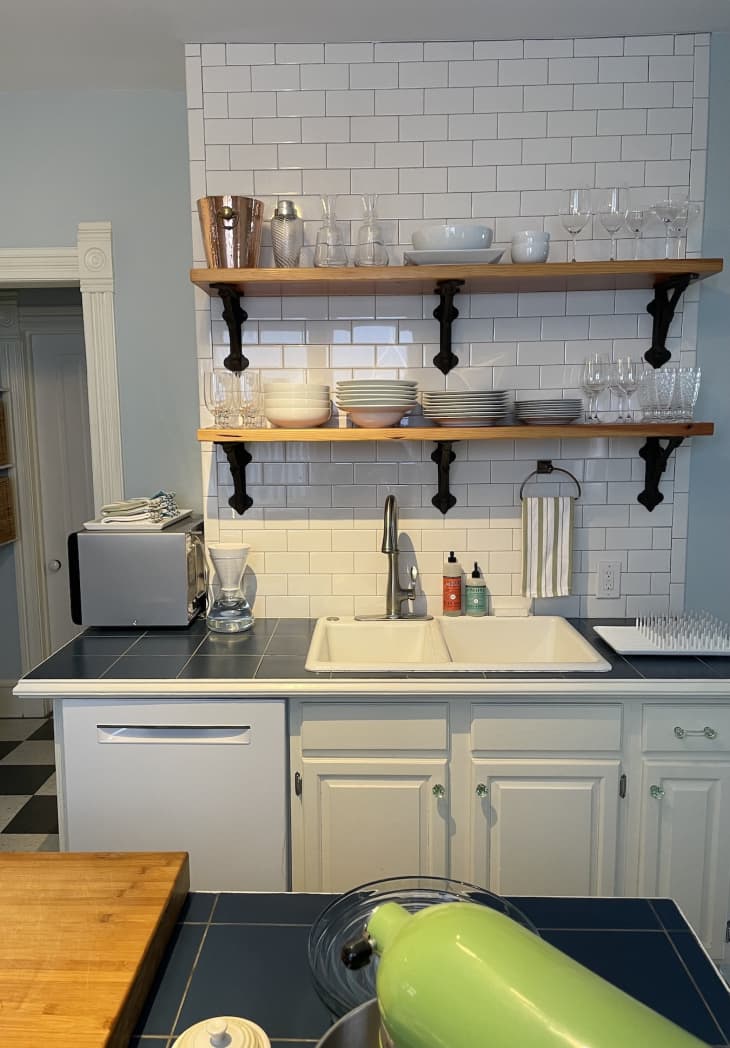 蓝色的厨房里有木制的浮动架子和白色的橱柜