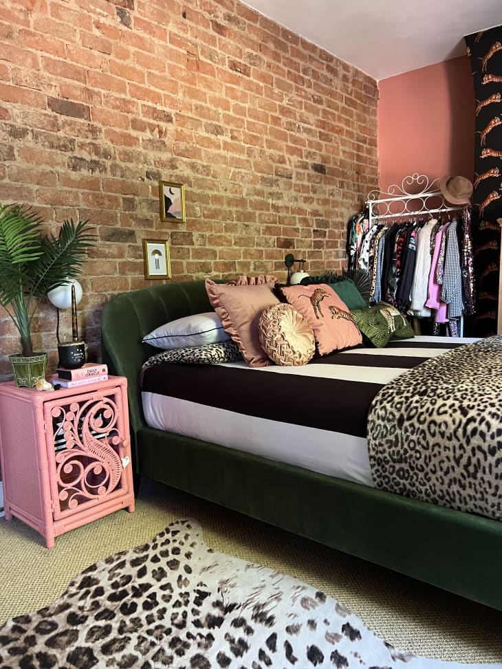 A bedroom with a brick wall and leopard print rug and blanket