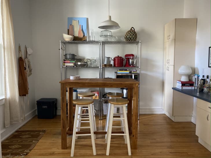 A brown table in front of metal kitchen shelves