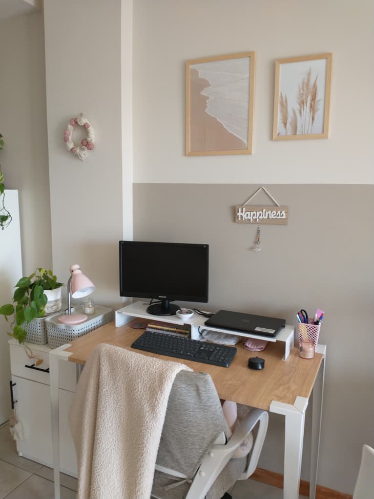 An office with a small white desk and art hanging above