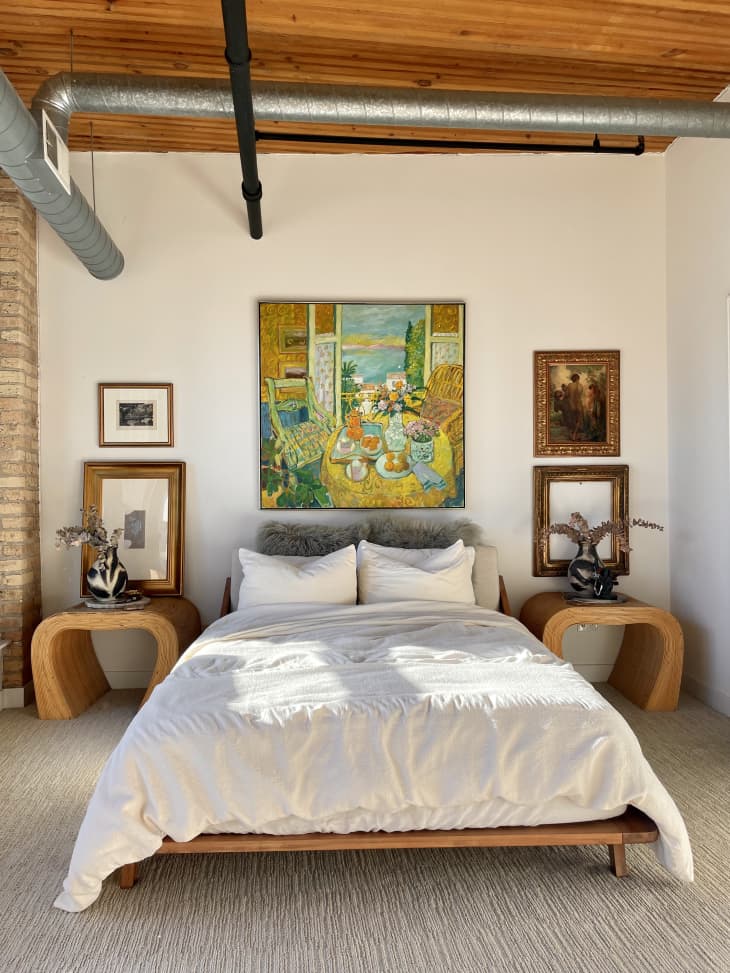 A white bedroom with art hanging above the bed
