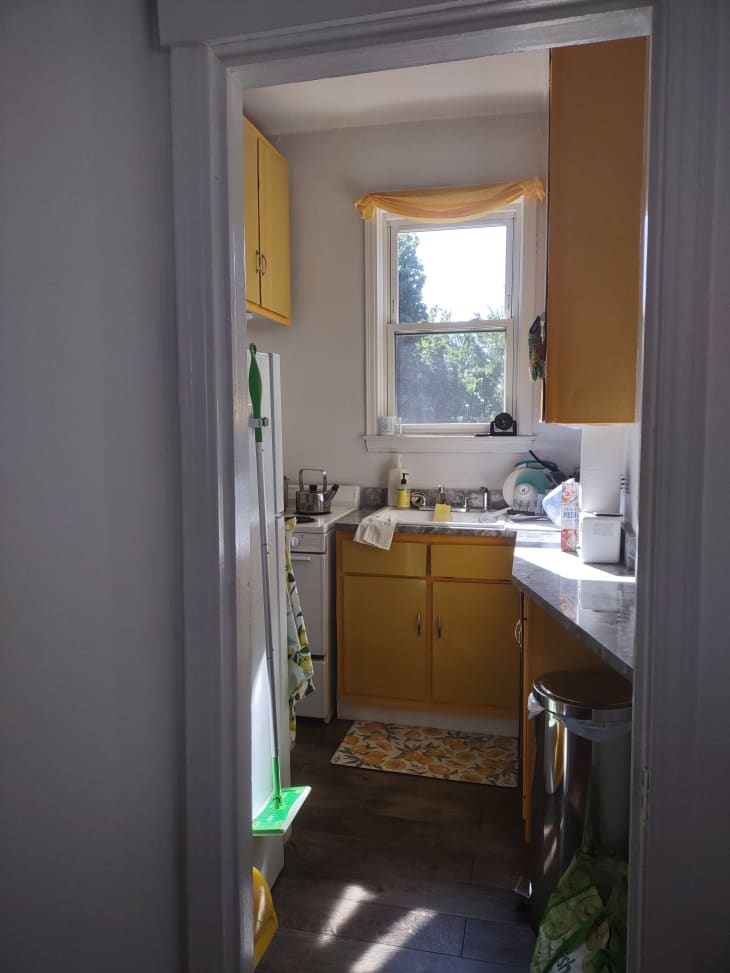 The entryway to a kitchen with a small window and yellow cabinets