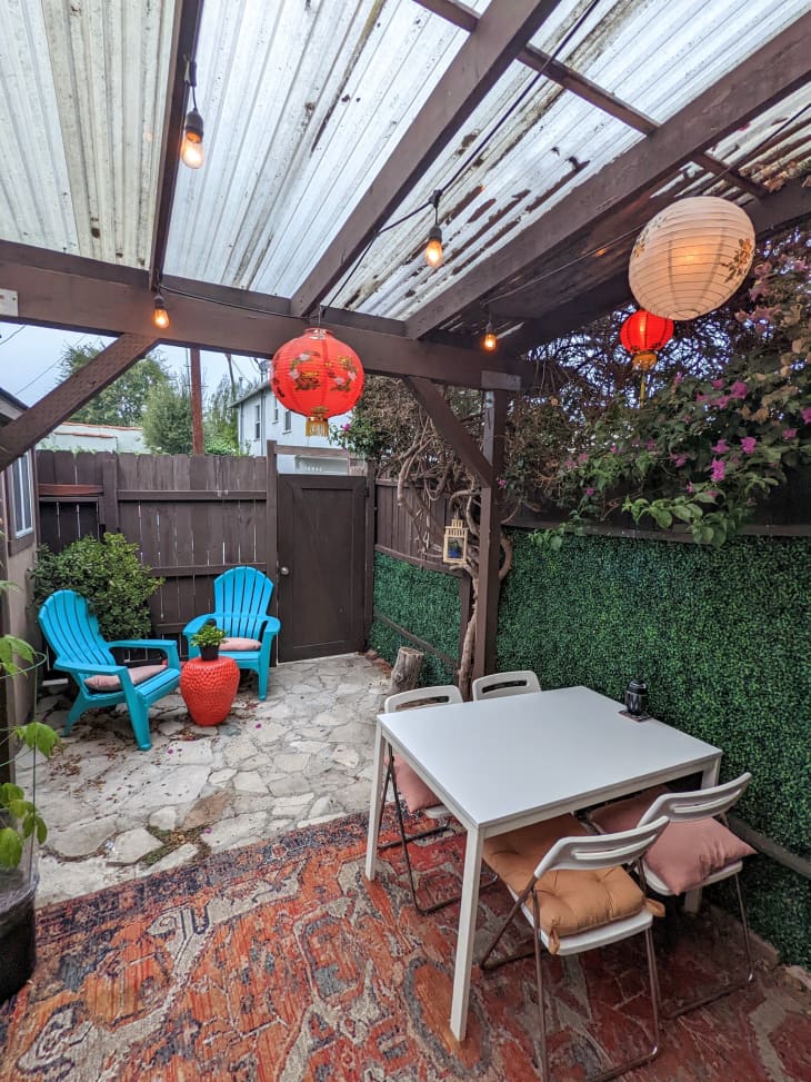 A covered backyard with two blue chairs and a table with chairs