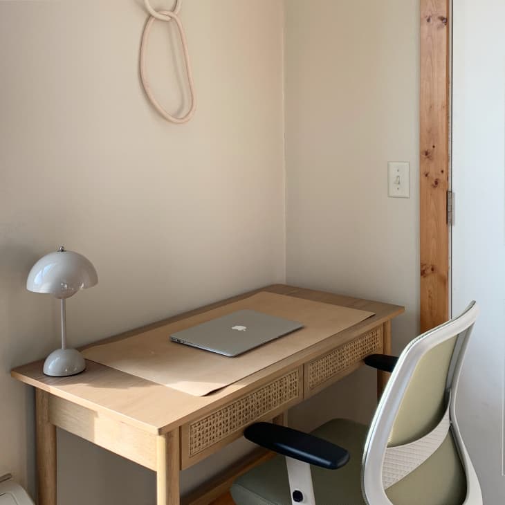 A wooden desk in the corner of a white room