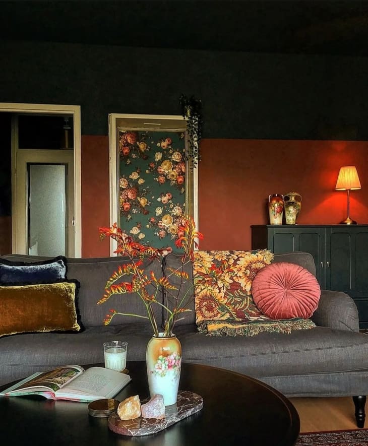A red living room with a gray couch and flowers on the coffee table