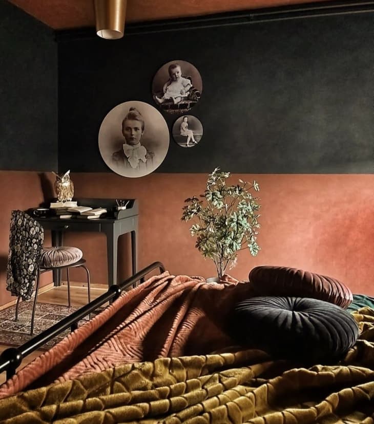 A bedroom with black and red walls and black and white photos