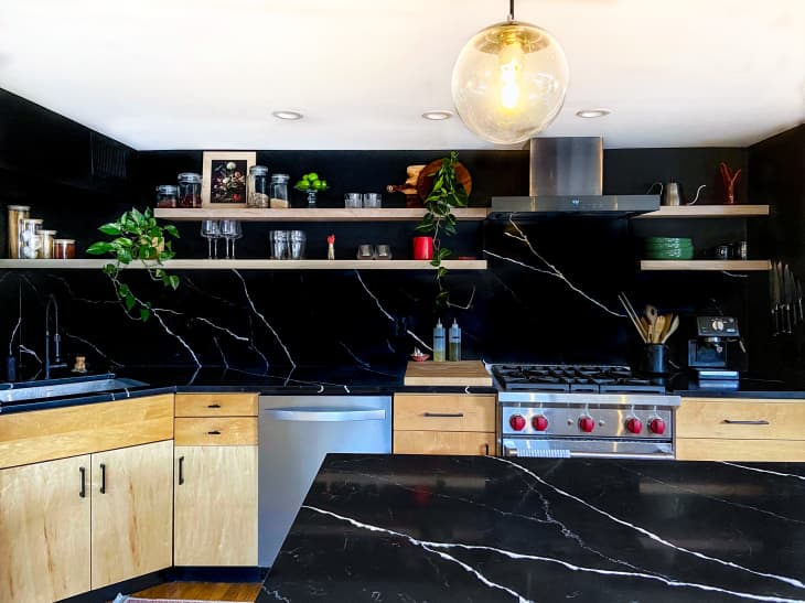 A large kitchen with black marble counters and walls