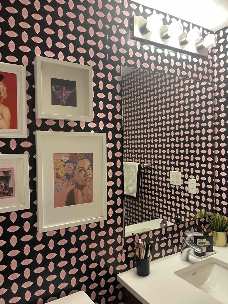A pink and black bathroom wall with art hanging