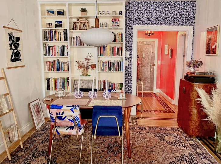 A dining room with a built-in bookcase and blue and white wallpaper