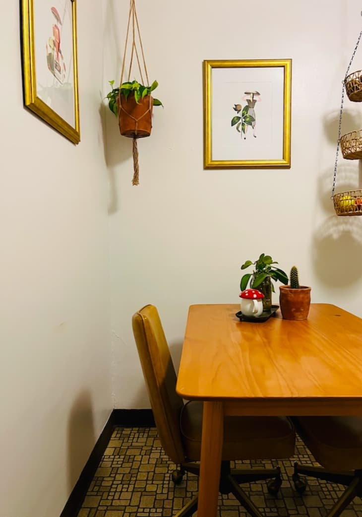 A wooden kitchen table with framed paintings on the walls