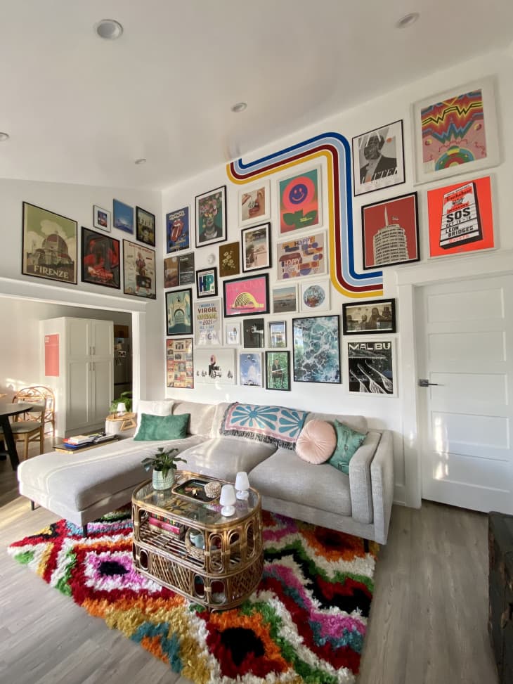 A living room with a large gallery wall on two walls and a colorful rug