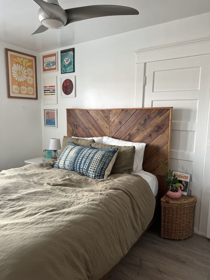 A tan blanket on a large bed with a wooden headboard