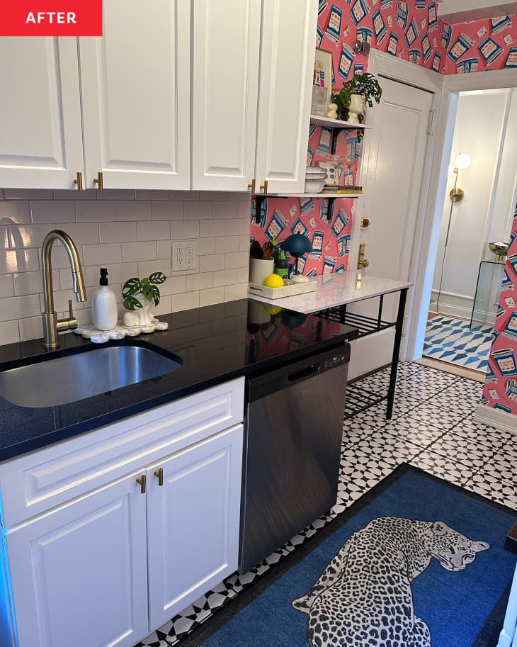 Kitchen after renovation with white cabinets and dark countertops and pink and blue wall paper on far wall.